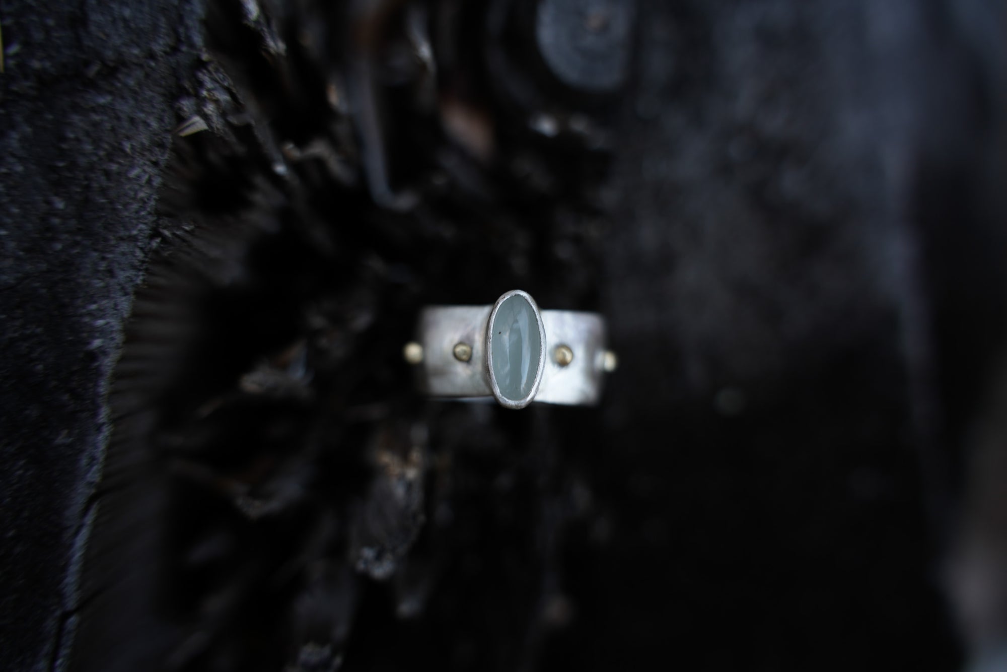A sterling silver ring with a blue aquamarine oval gemstone set against a blurred background.