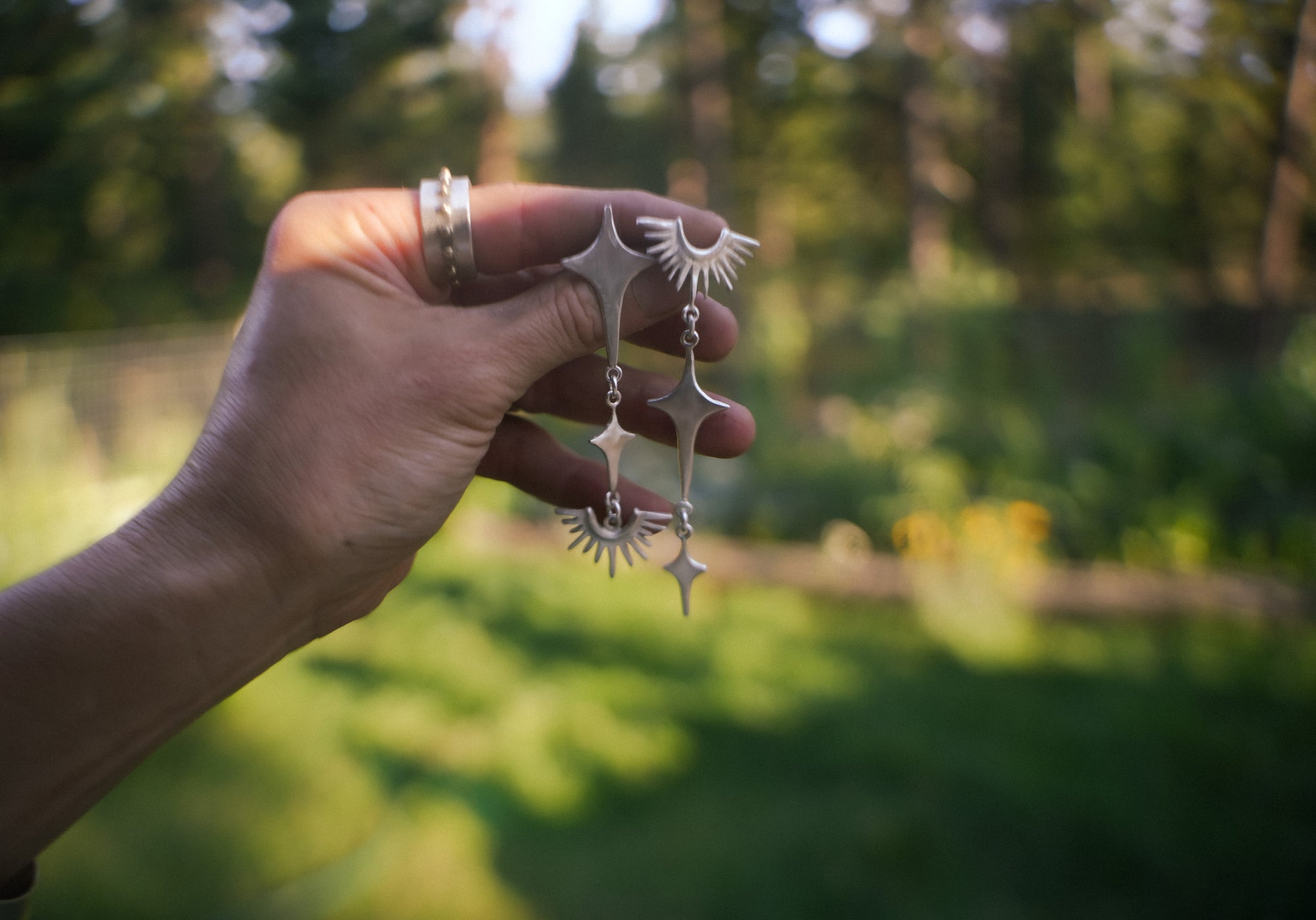Reclaimed asymmetrical sterling silver post earrings. Stars and horizon line symbols dangle from the larger star at the top.